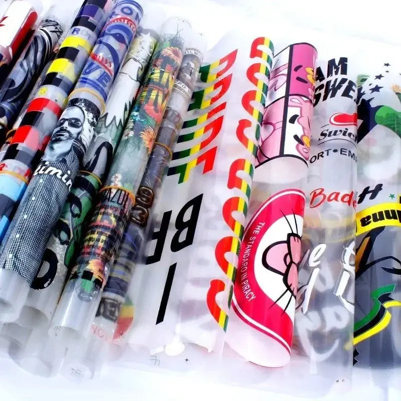 Rolled DTF gang sheets displaying assorted colorful apparel designs.