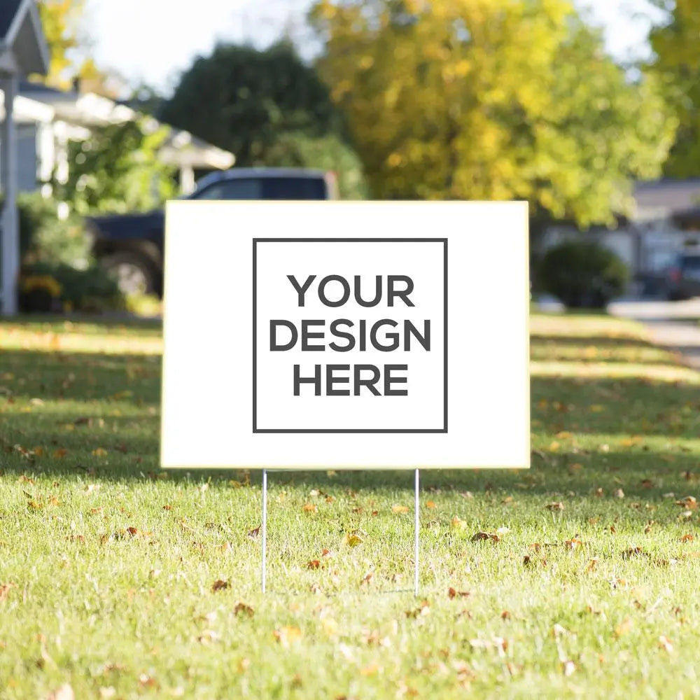 White yard sign on wire stakes in a lawn with Your Design Here placeholder artwork.