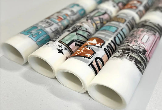 Rolled printed transfer sheets showing assorted full-color designs.