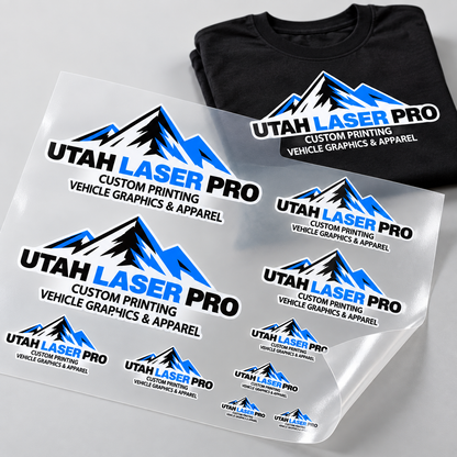 Mockup of Utah Laser Pro logo transfers in multiple sizes on a DTF gang sheet beside a matching black T-shirt.